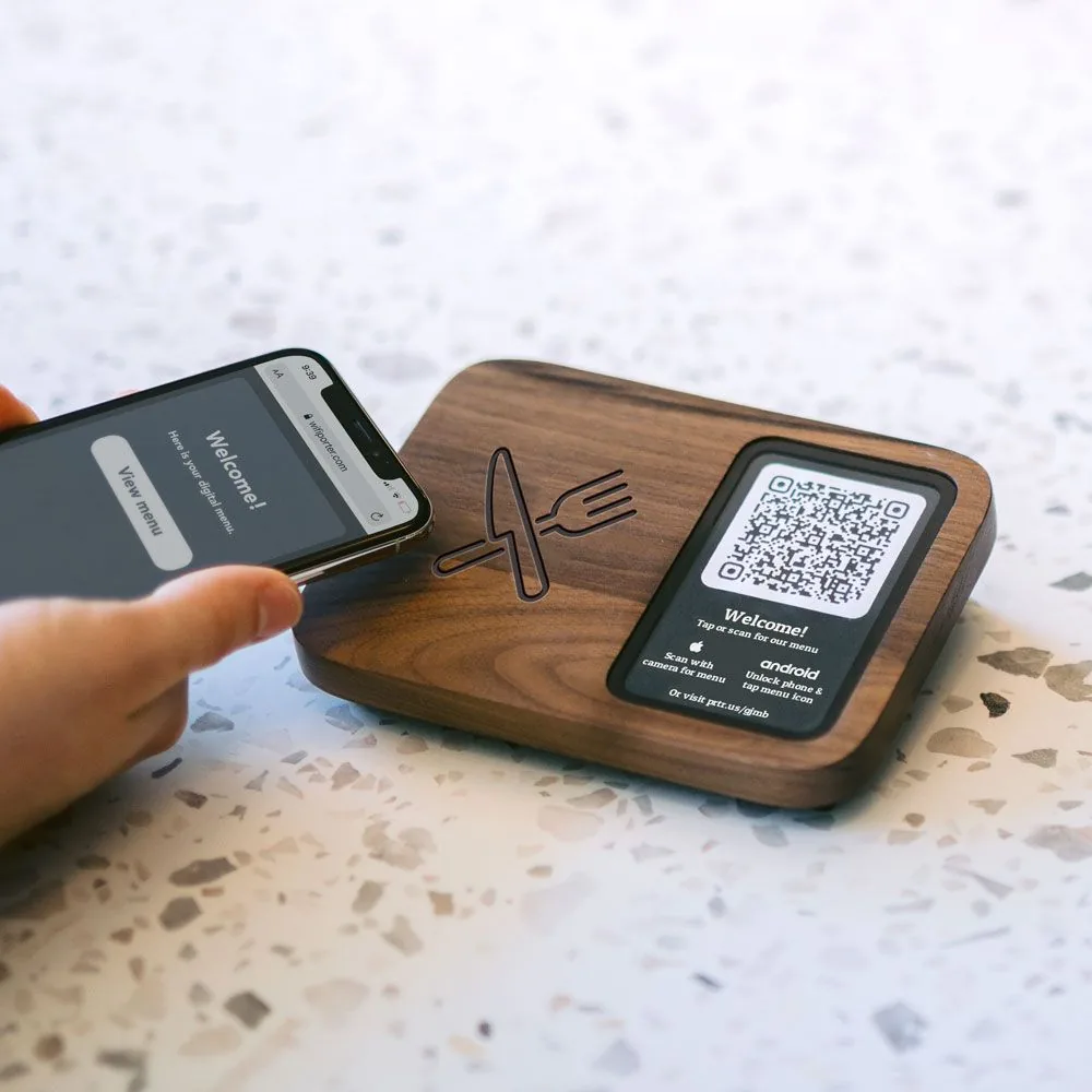 Celular tocando uma placa NFC de madeira no balcão